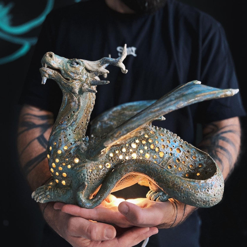 Person holding a dragon-shaped lantern with intricate details against a dark background