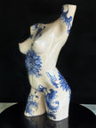 Ceramic figurine of a torso with blue floral patterns on a black background