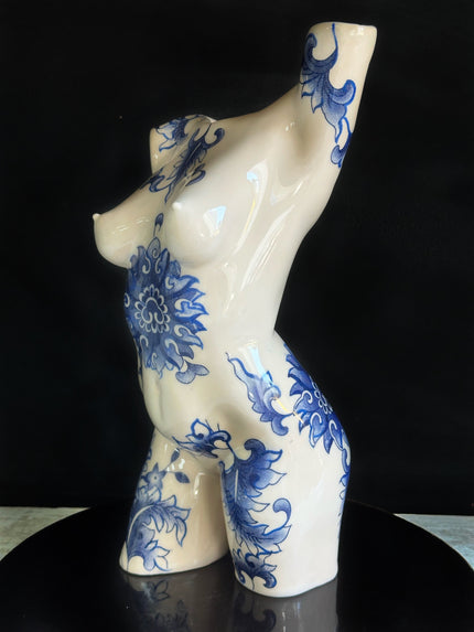 Ceramic figurine of a torso with blue floral patterns on a black background