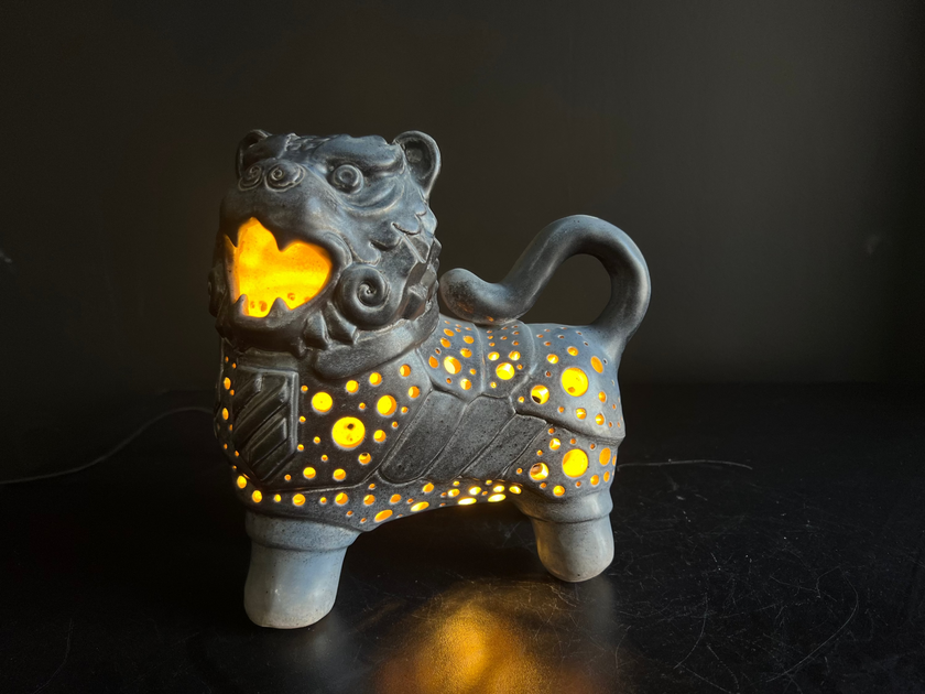Ceramic lion figurine with glowing yellow interior on a dark background