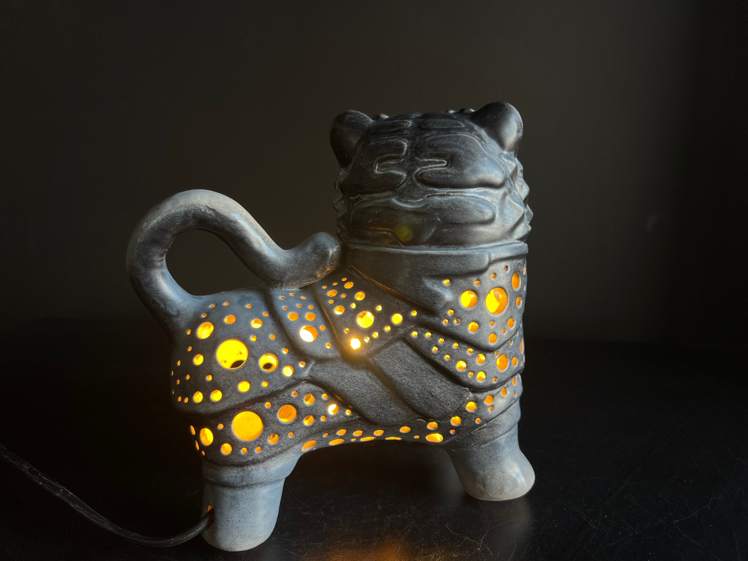 Ceramic tiger-shaped lamp with glowing interior on a black background