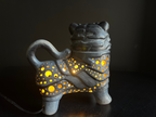 Ceramic tiger-shaped lamp with glowing interior on a black background