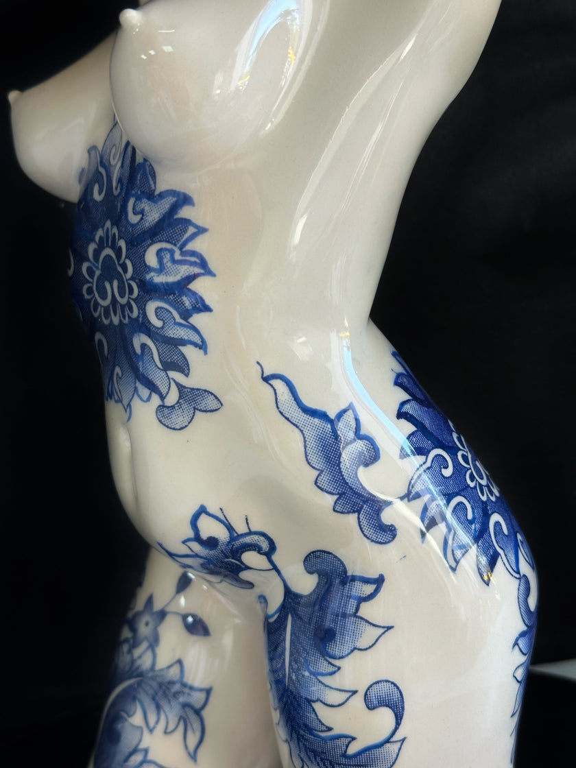 White ceramic figure with blue floral patterns on a black background