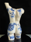 Ceramic vase shaped like a torso with blue floral patterns on a black background