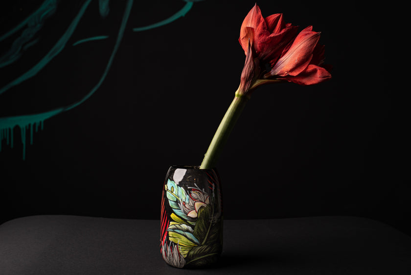 Red flower in a colorful vase against a black background