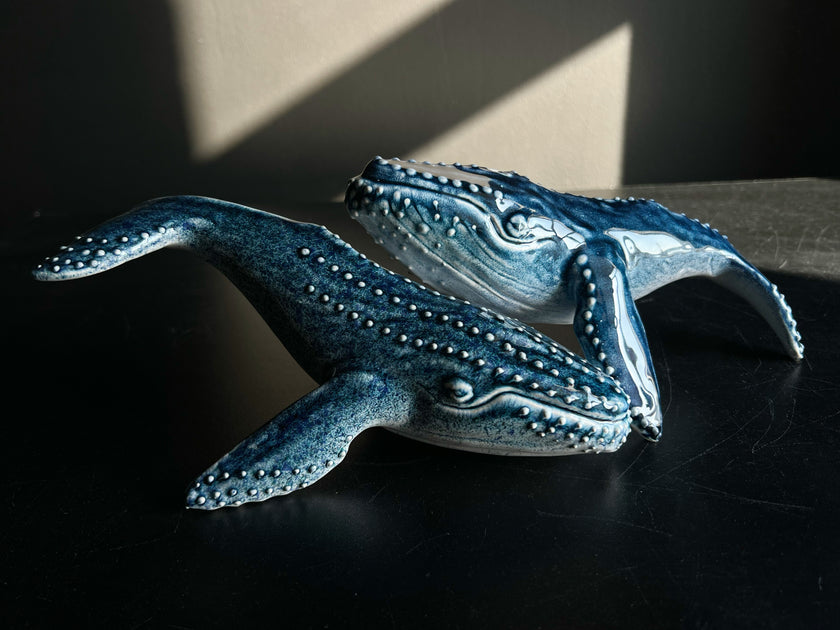 Blue ceramic whale sculpture on a dark surface