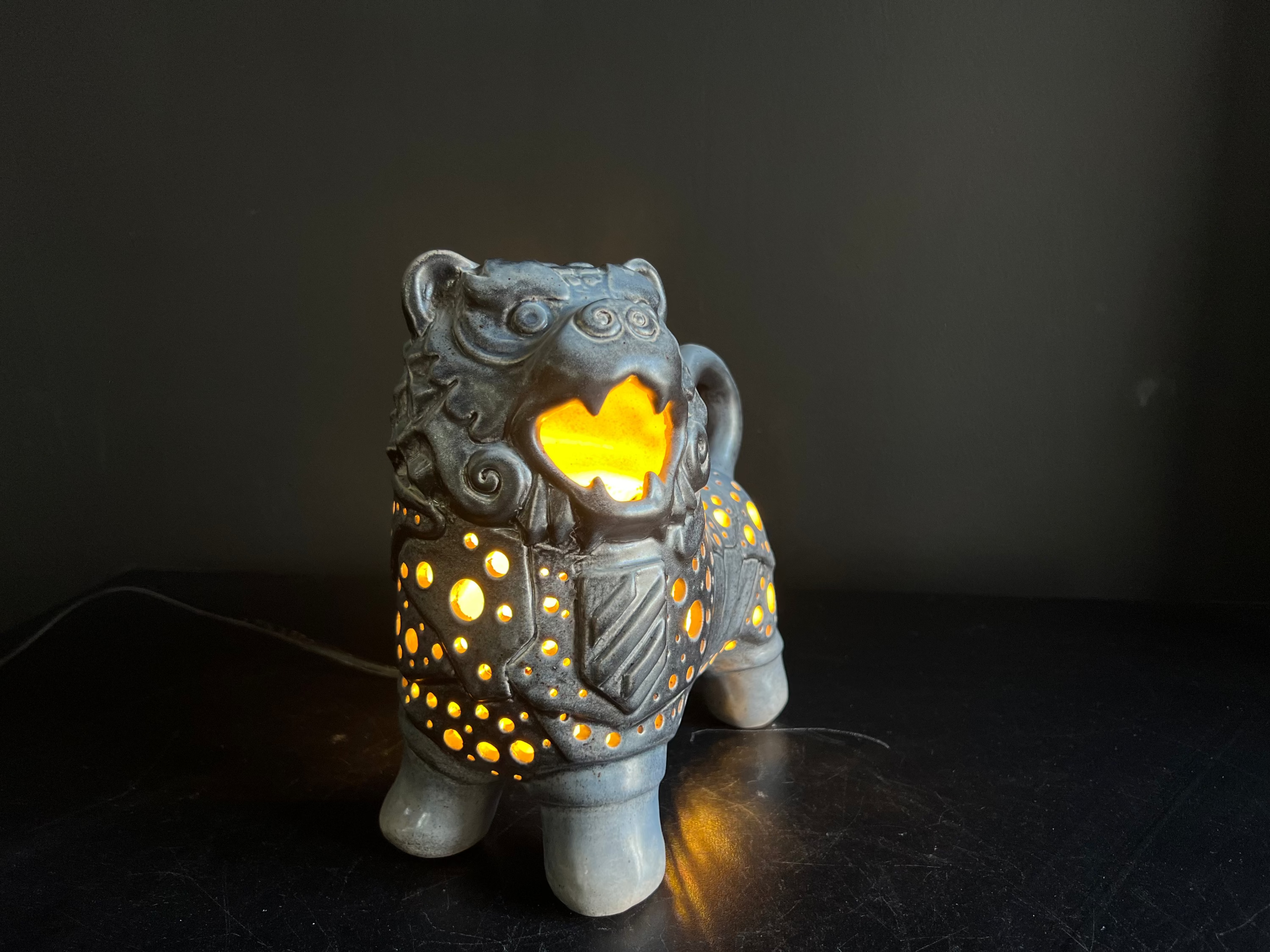 Ceramic lion-shaped lamp with a warm glow on a dark background