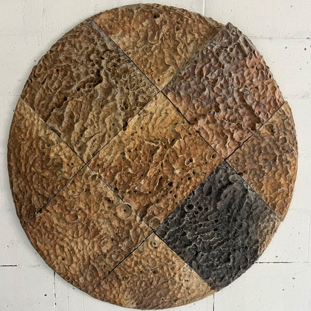 Round textured wall art piece with brown and gray tones on a white background