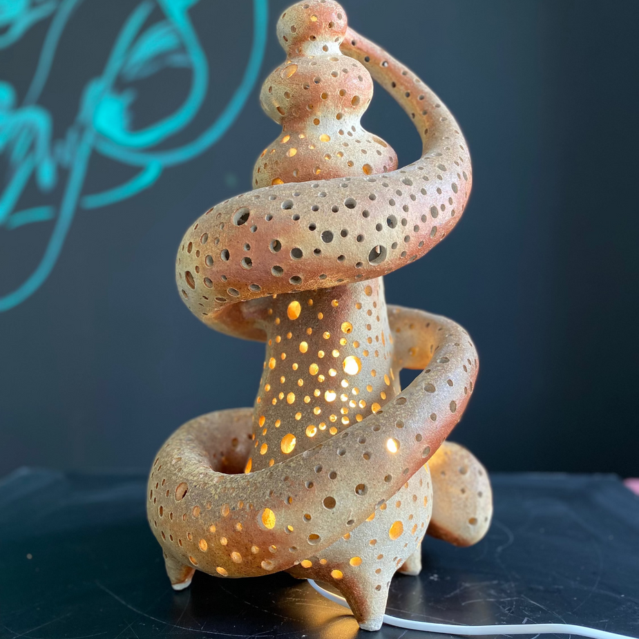 Ceramic sculpture with a glowing interior on a dark surface