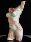 White ceramic sculpture with red floral patterns on a black background