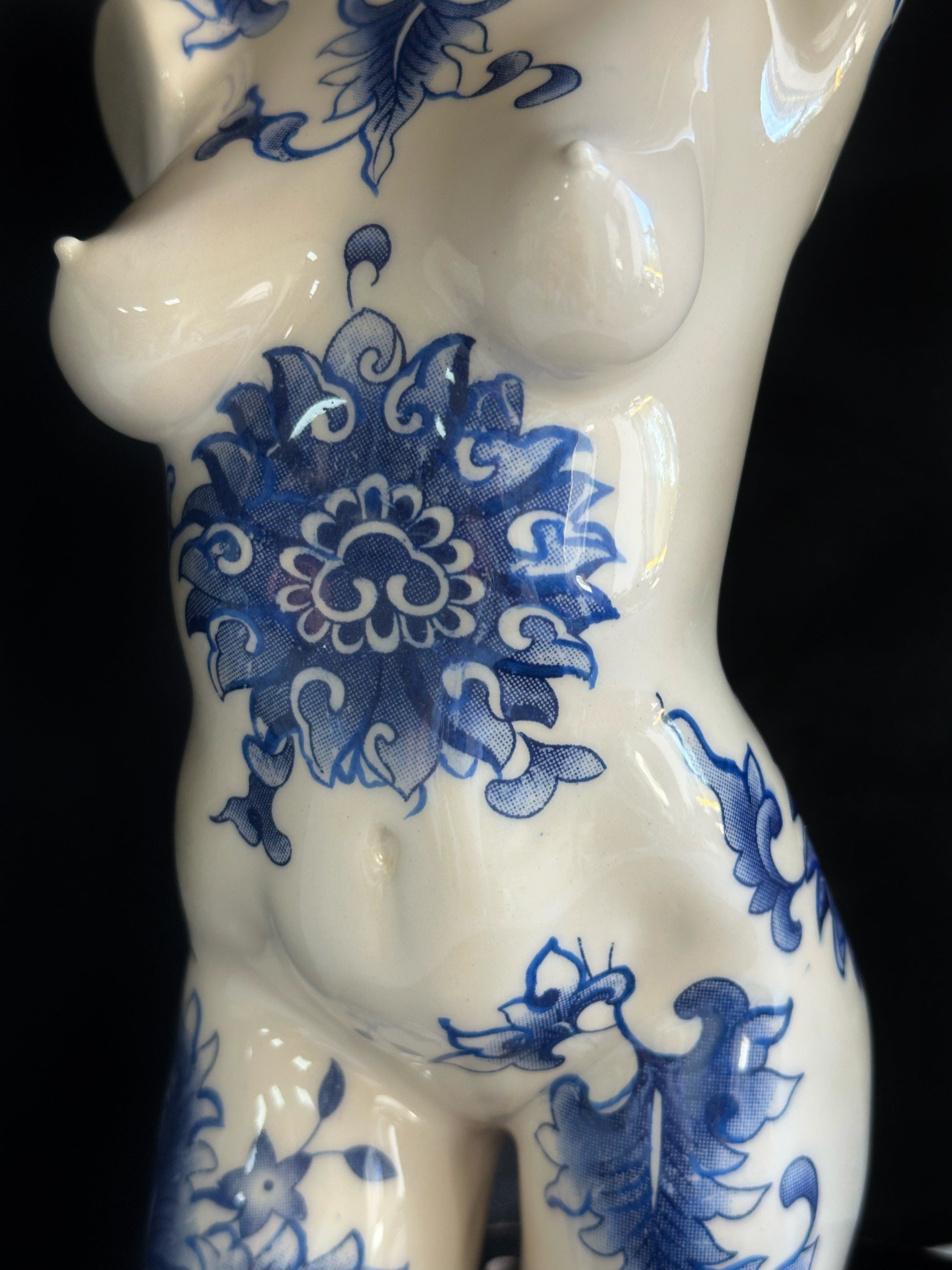 White ceramic figurine with blue floral patterns on a black background