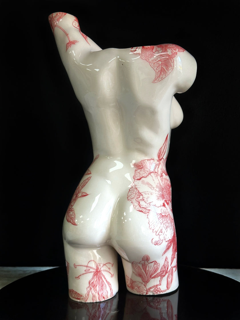 White ceramic figure with red floral patterns on a black background